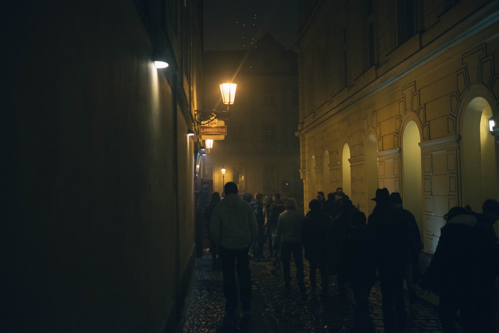 a group of people walking down a street at night