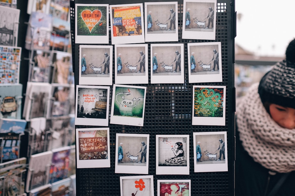 a woman standing next to a wall covered in pictures