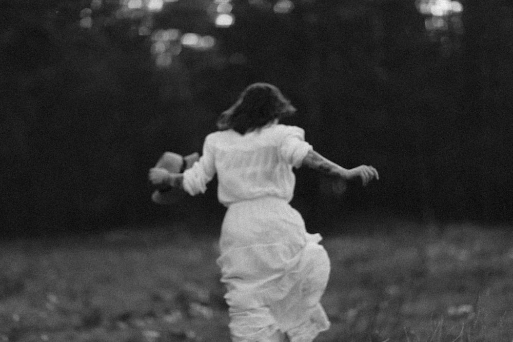 a woman in a white dress running through a field