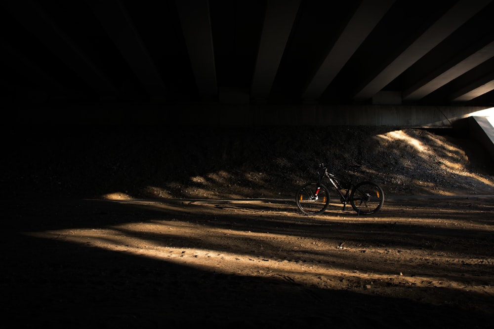 Un vélo garé sous un pont dans l’obscurité