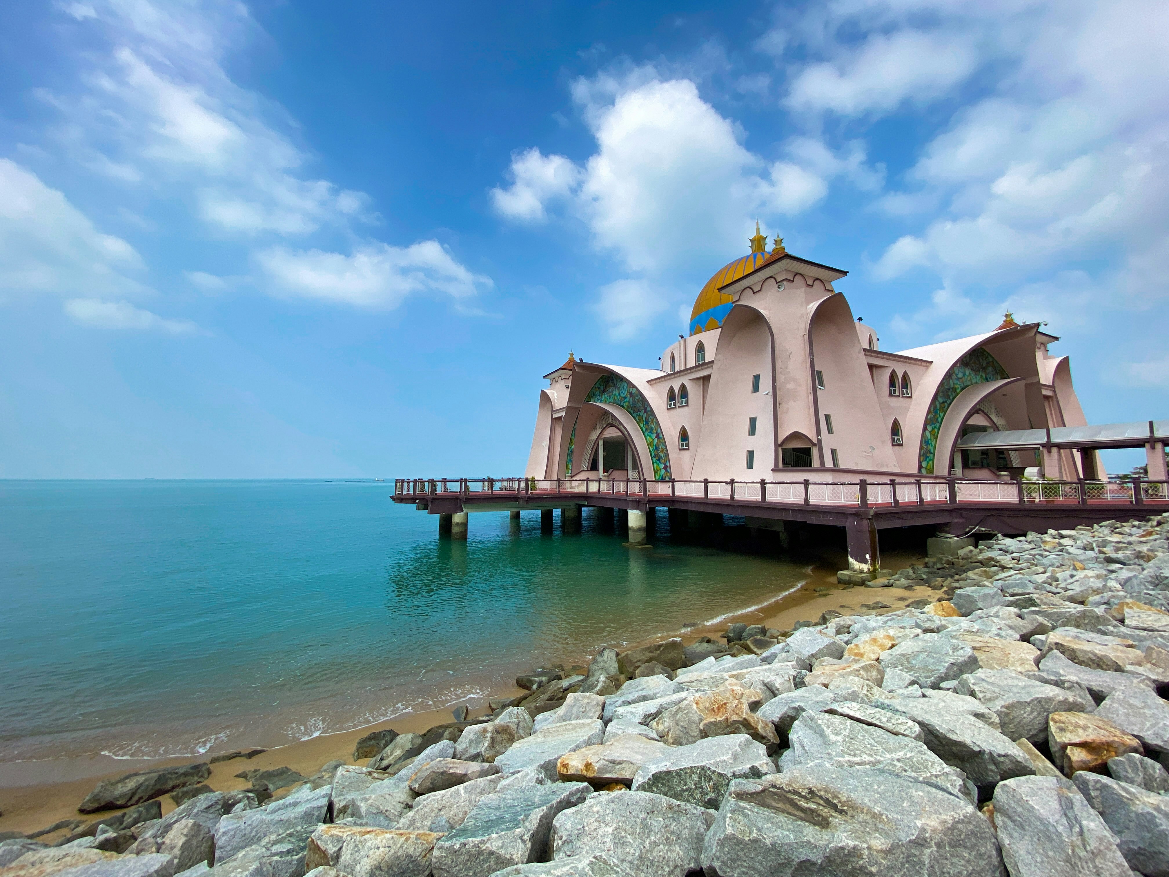 a pink building sitting on top of a pier next to the ocean
