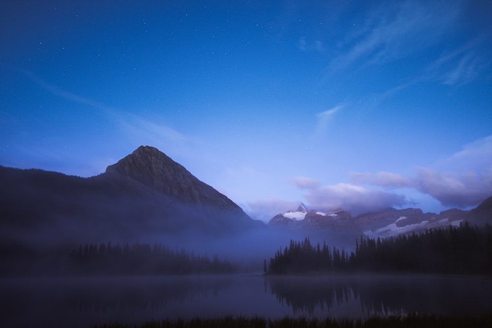 a lake surrounded by mountains under a blue sky