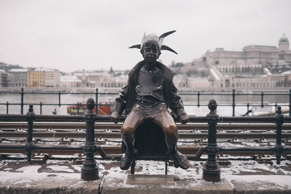 a statue of a man sitting on top of a bench