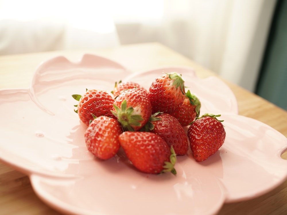a bunch of strawberries on a pink plate