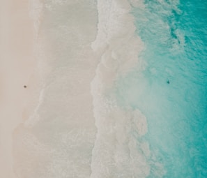 An aerial perspective of a serene beach with turquoise waves gently crashing on the shore.