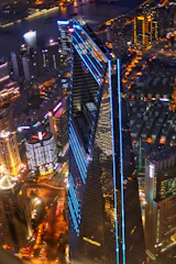 A sleek nighttime aerial shot of a luxury real estate property illuminated with blue accent lighting.