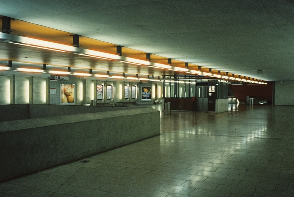 an empty subway station with lights on the ceiling