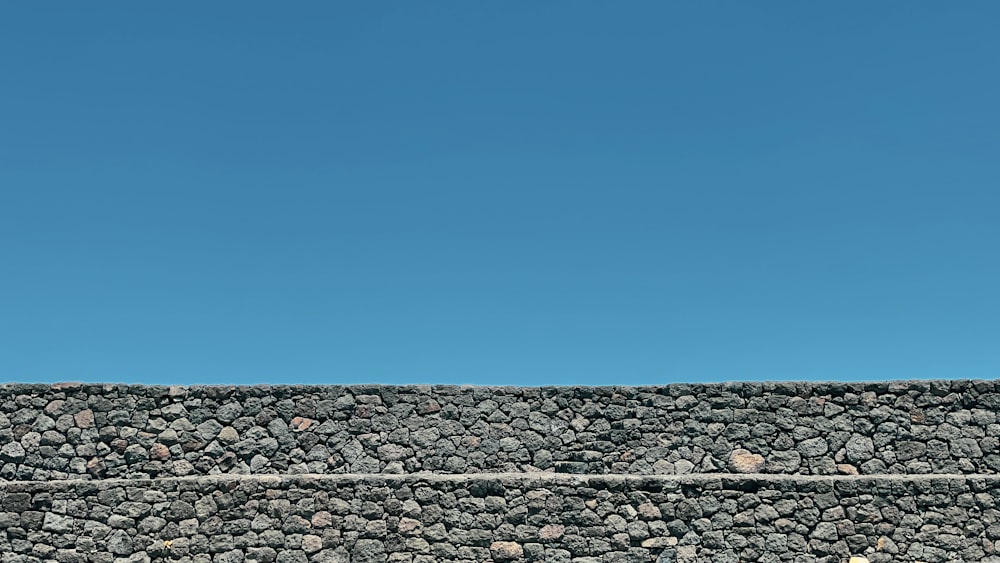 a man riding a skateboard on top of a stone wall
