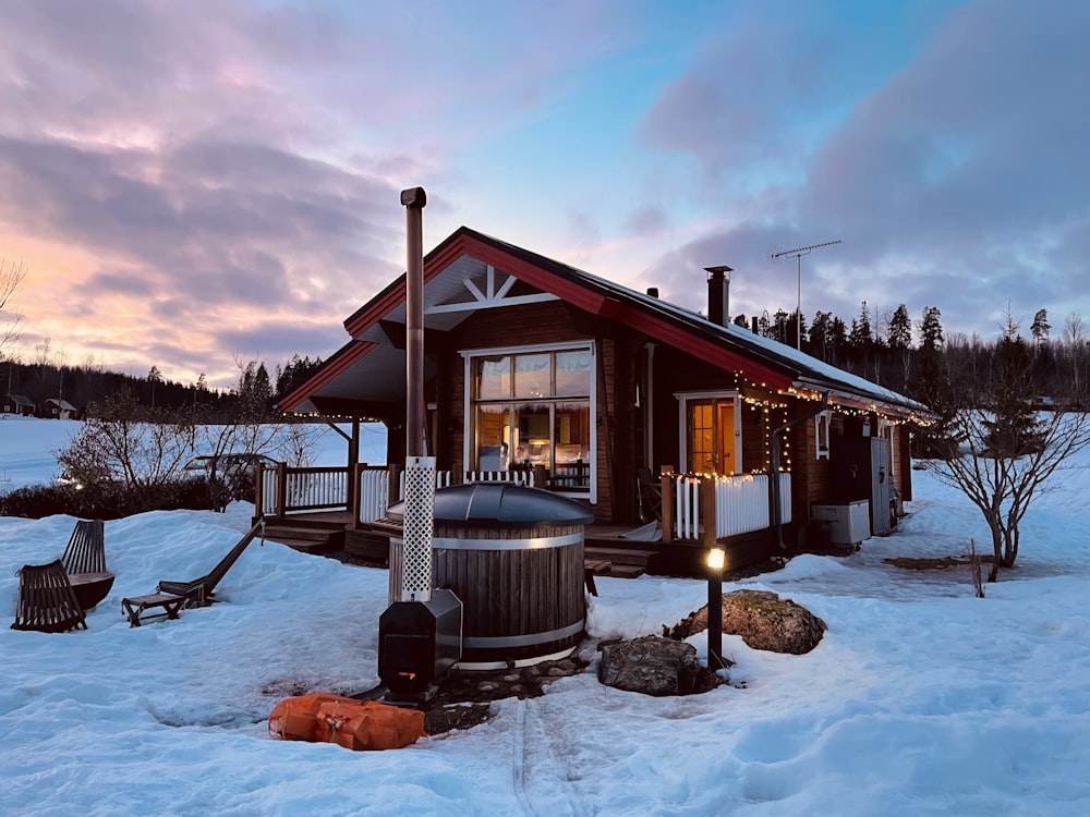 a small cabin with a hot tub in the snow