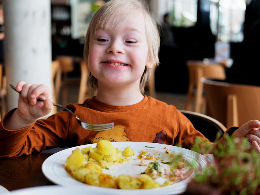 Smiling little boy eating happily from his plate at home