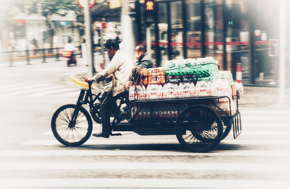 a man riding a bike with a cart full of bottles on the back of it
