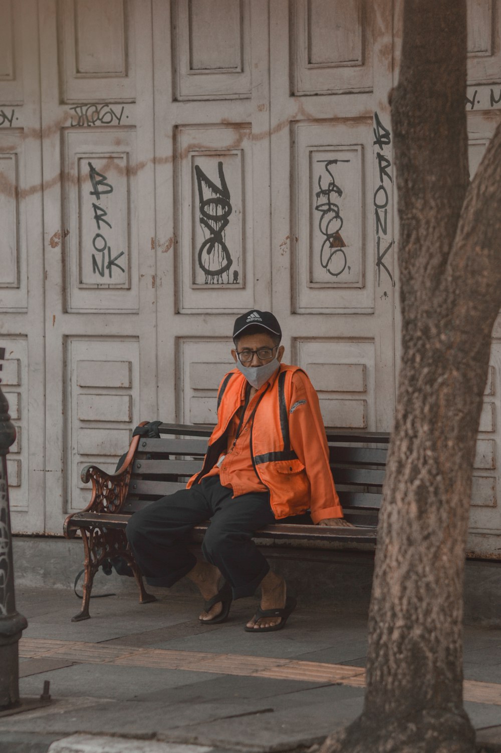 a man in an orange jacket sitting on a bench