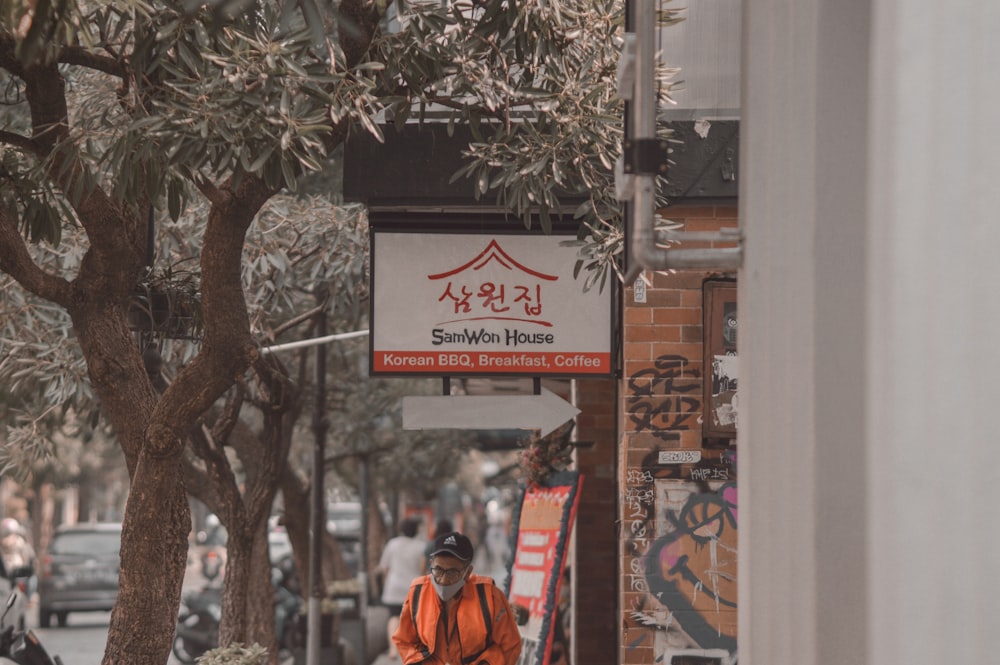 a man walking down a street next to a tree