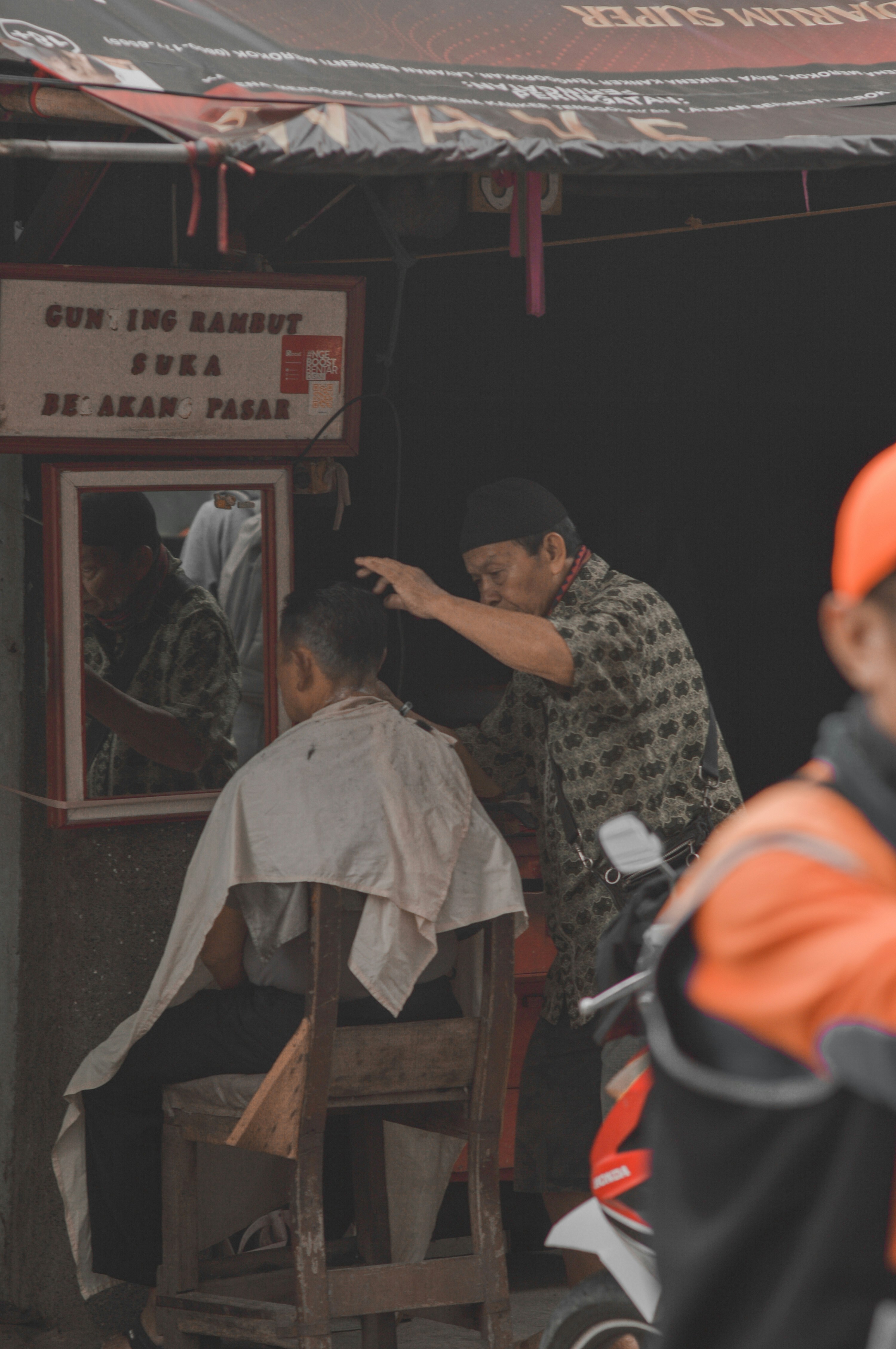 seorang pria memotong rambut pria lain di toko pangkas rambut