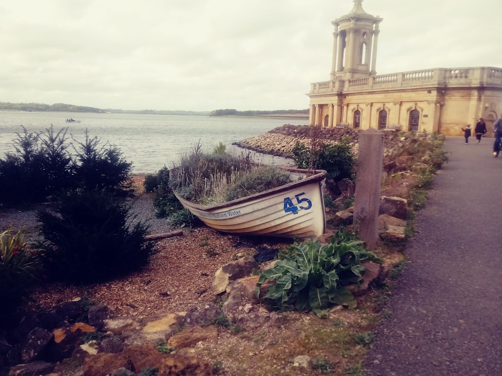 a boat sitting on the side of a road next to a body of water