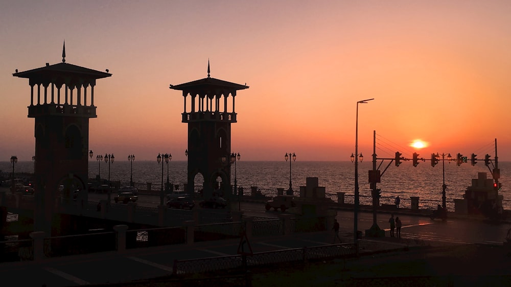 the sun is setting over the ocean with a pier in the foreground