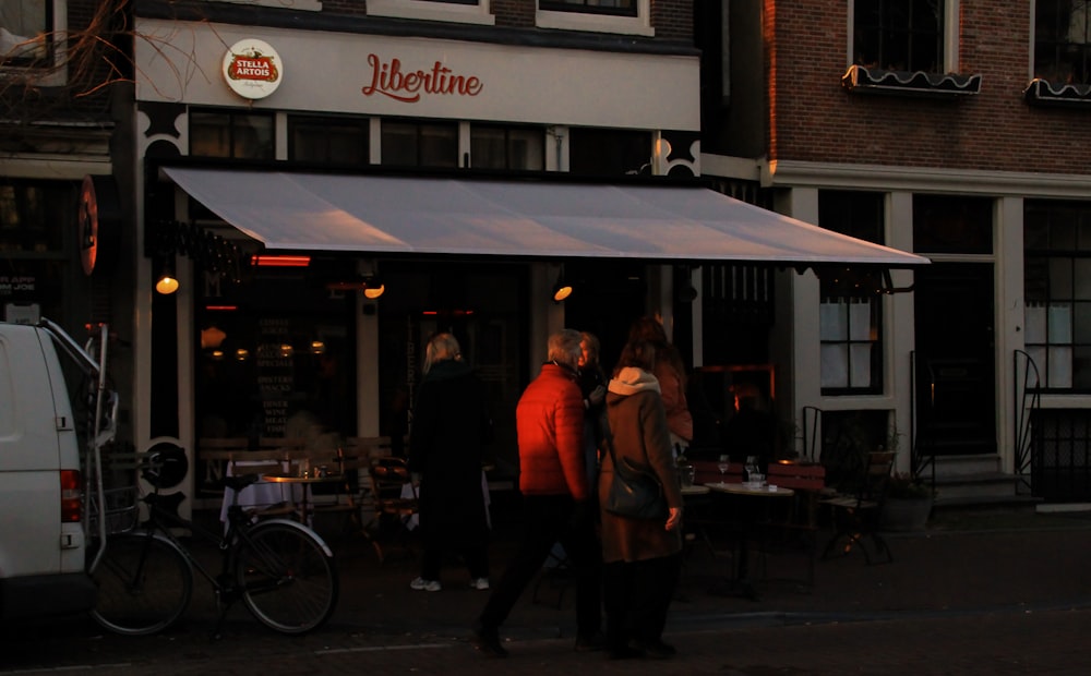 a group of people standing outside of a restaurant