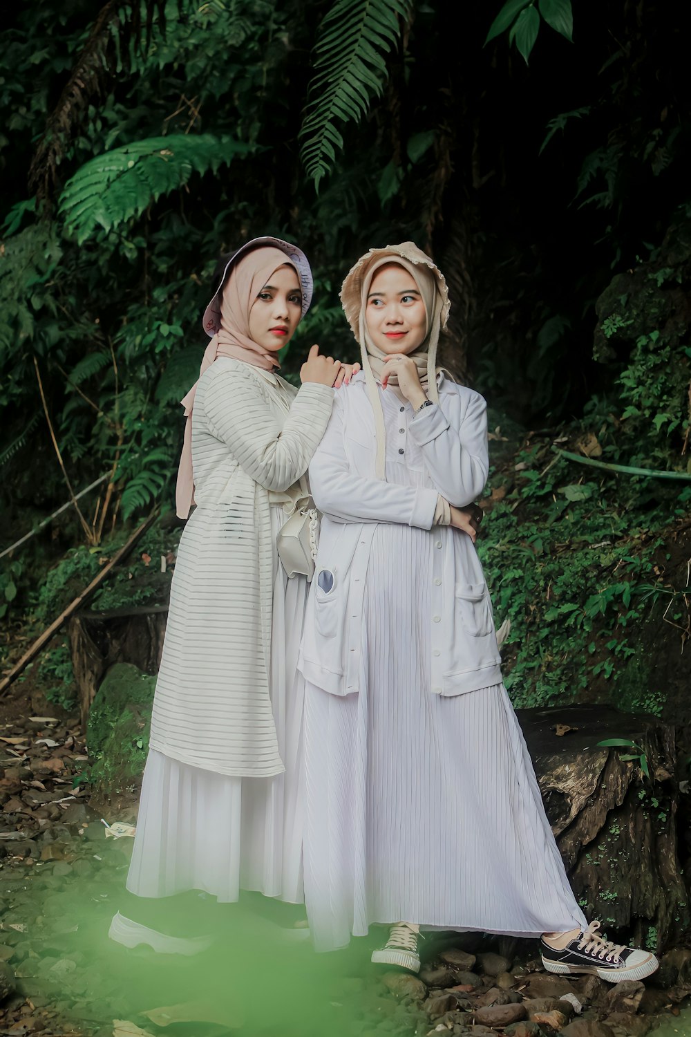 two women standing next to each other in a forest