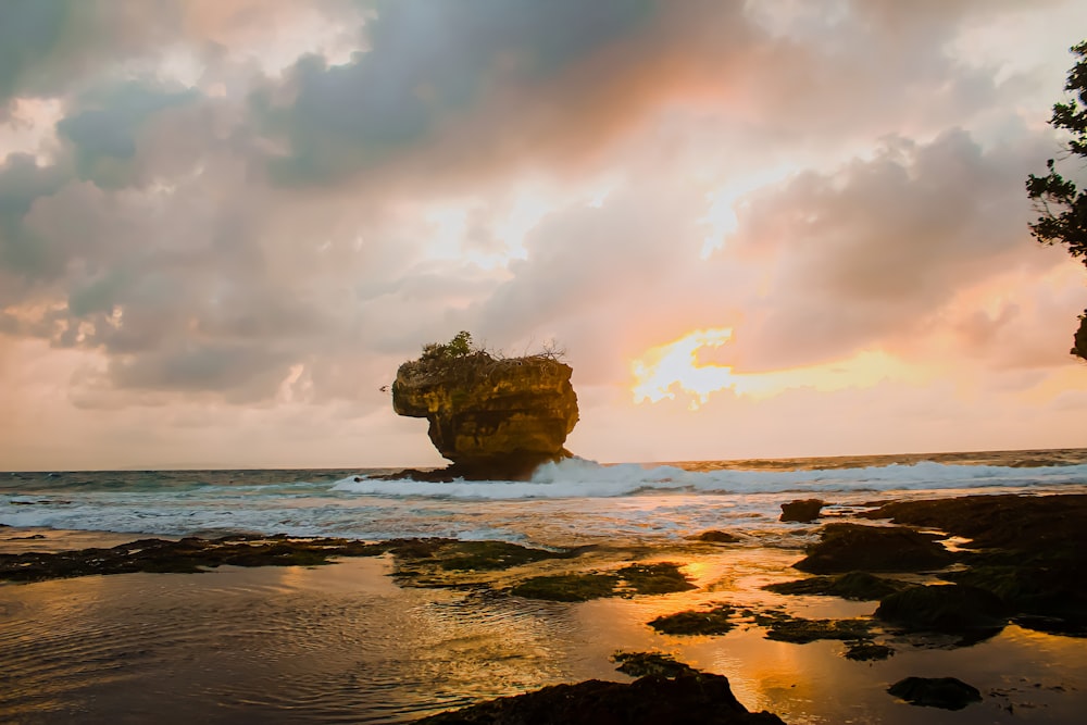 a large rock sitting on top of a beach next to the ocean