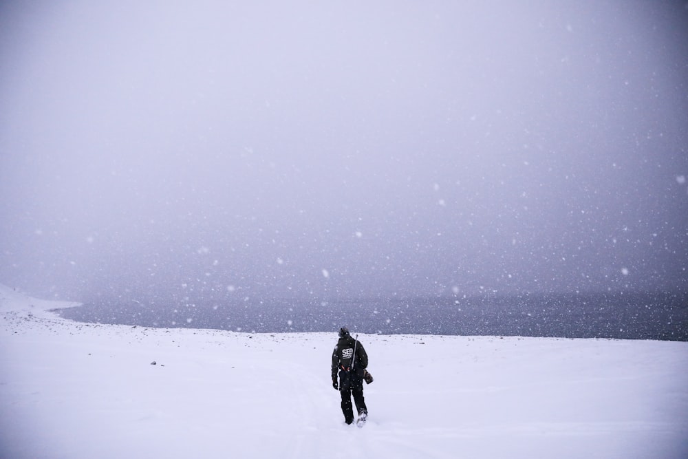 um homem andando através de um campo coberto de neve