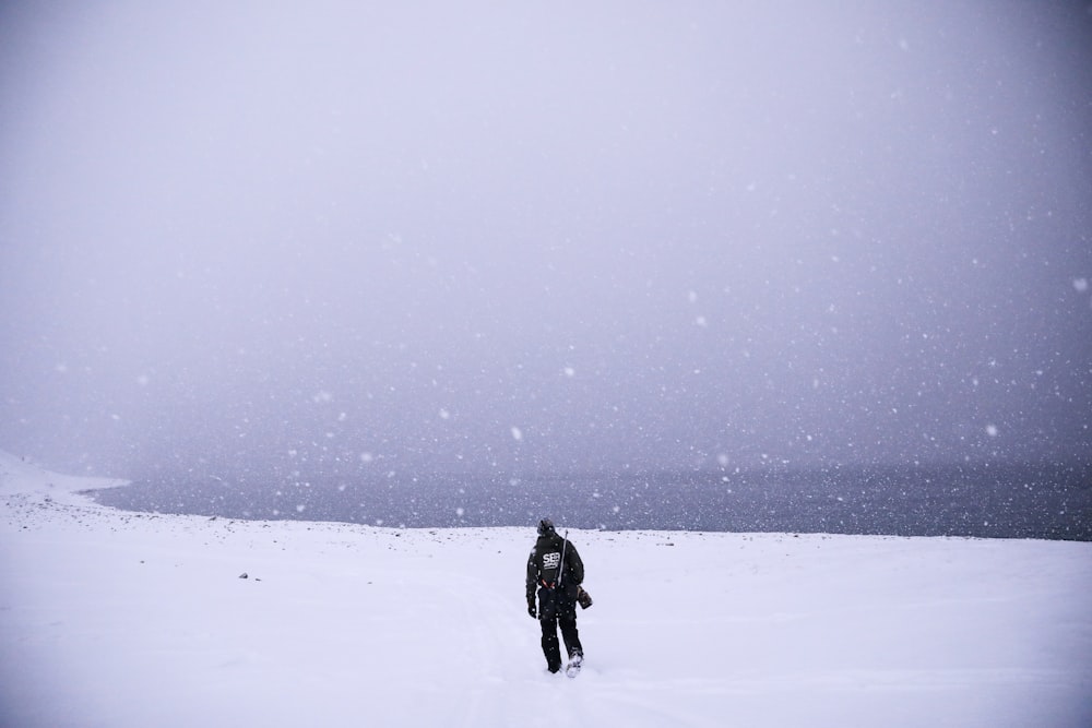 a man walking across a snow covered field