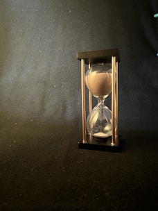 A sleek, modern hourglass with glowing sand trickling down, symbolizing anticipation.