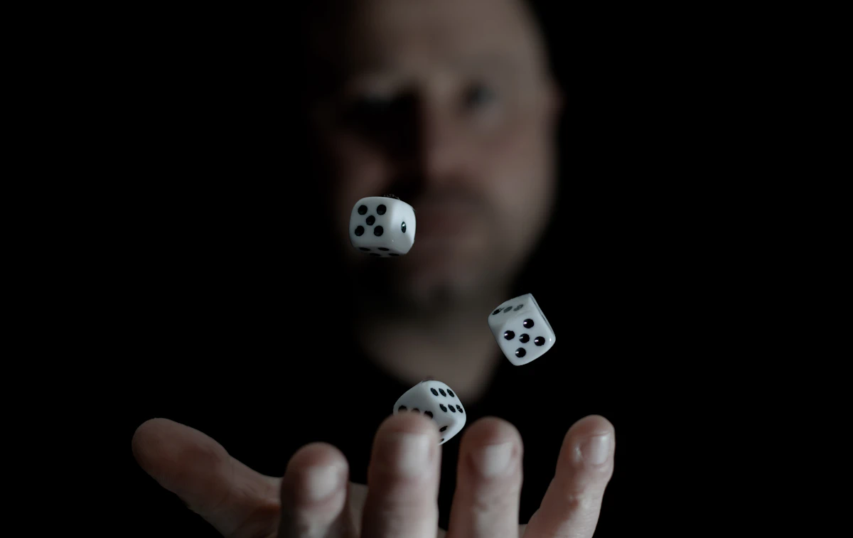 A man tosses dice into the air against a dark background