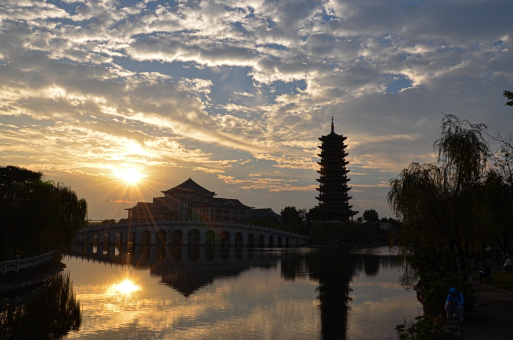 the sun is setting over a bridge over a body of water