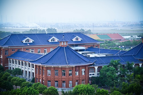 a large building with a blue roof surrounded by trees
