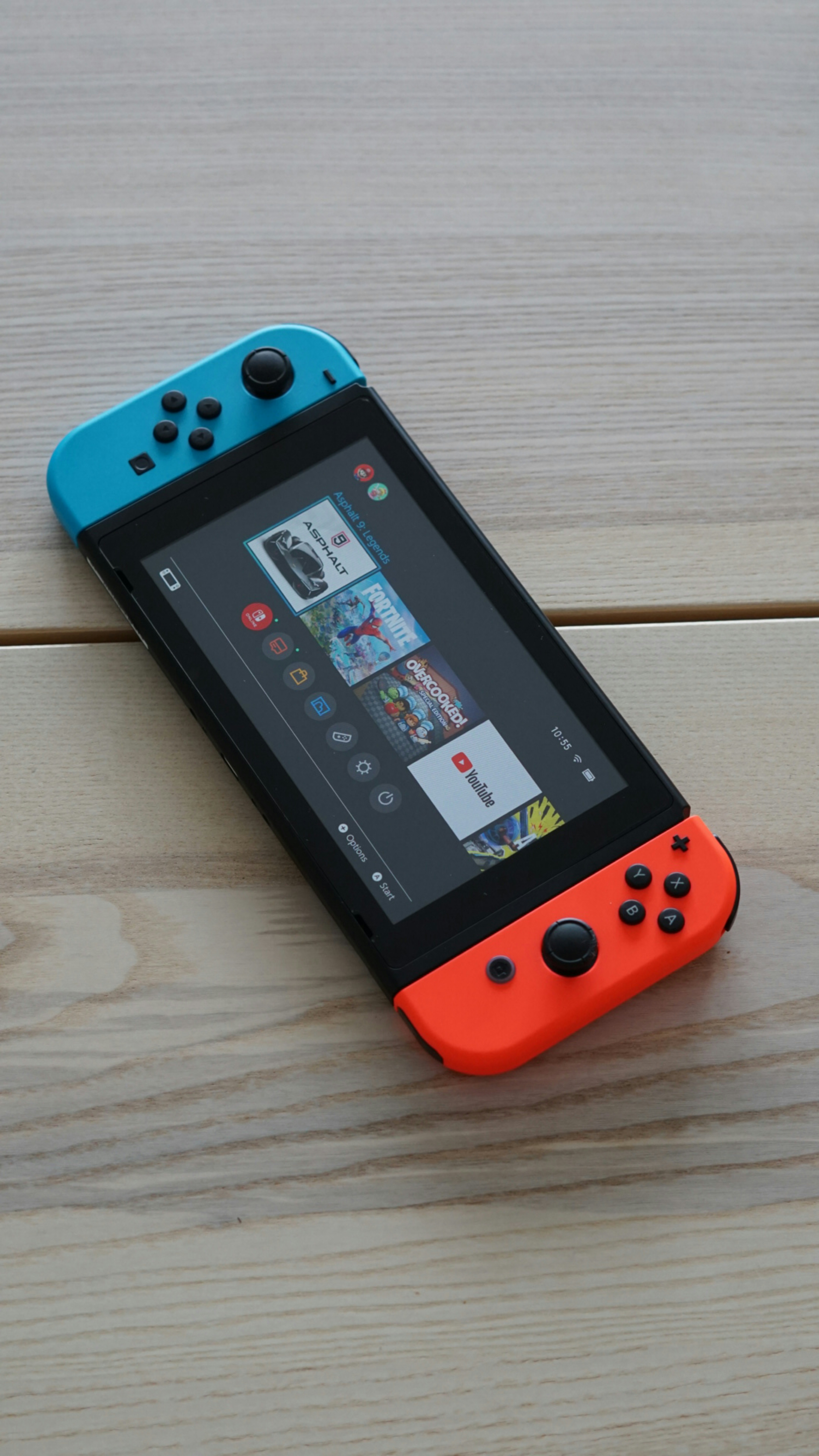 Un Nintendo Switch naranja y azul sentado encima de una mesa de madera