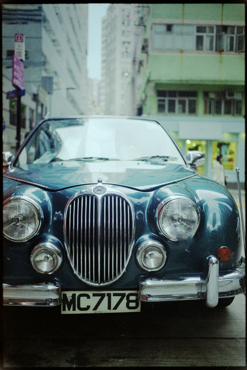 a blue car parked in front of a tall building