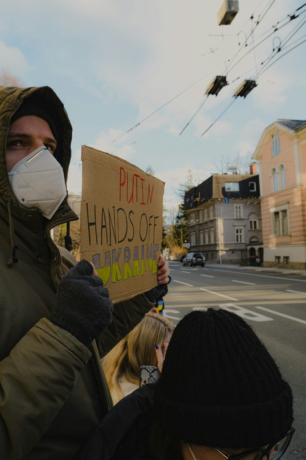 a man holding a sign while wearing a mask