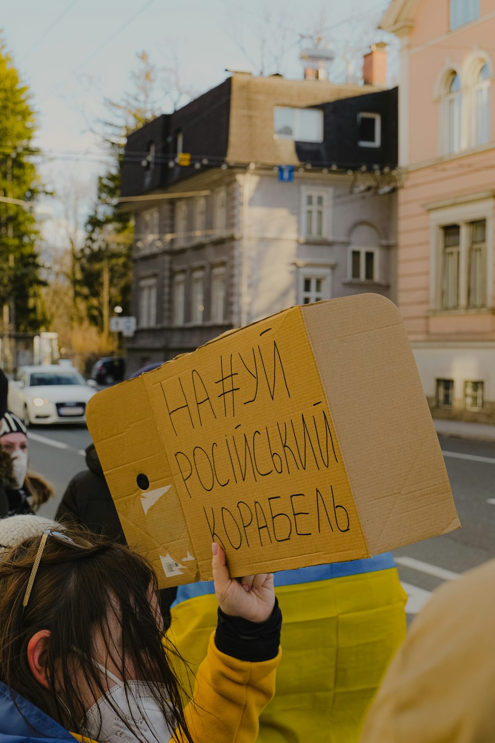 a woman holding a cardboard sign in the middle of a street