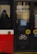 Reflection of a person wearing a mask is visible on the glass of a public transportation vehicle. Various symbols, including a bicycle and several circular buttons, are apparent on the door. The bottom section of the vehicle is red and white.