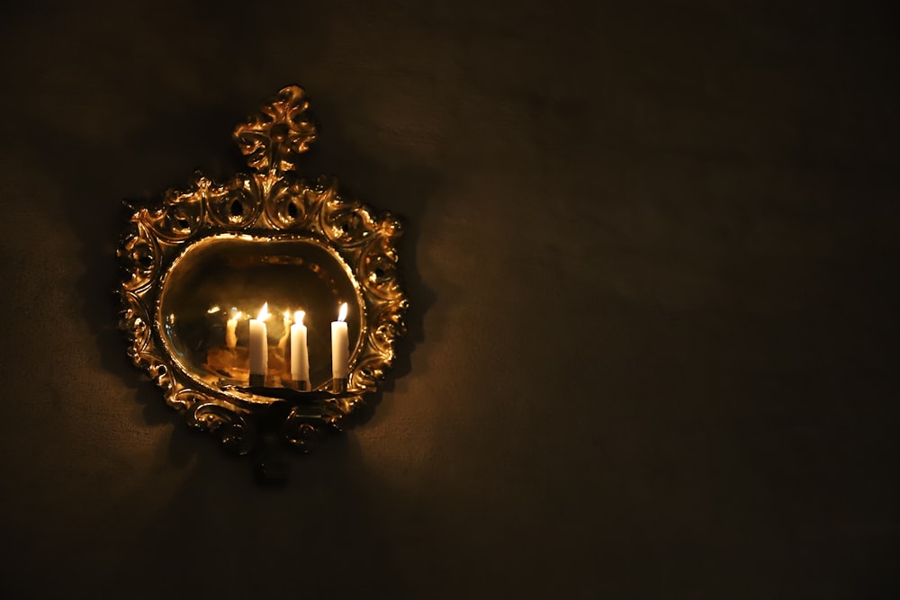 a wall mounted mirror with a lit candle inside of it