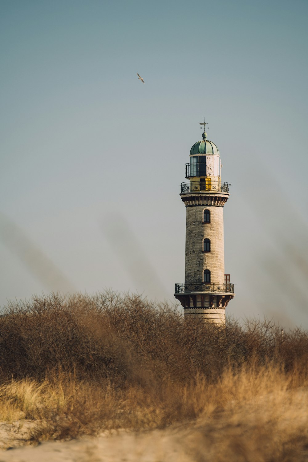 a tall light house sitting on top of a dry grass covered field