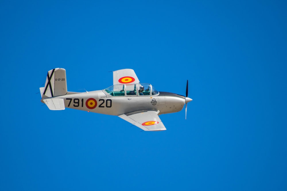 a small airplane flying through a blue sky