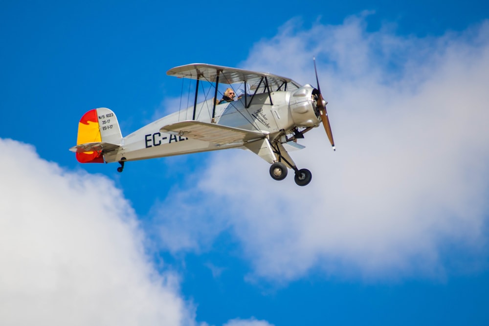 a small airplane flying through a cloudy blue sky