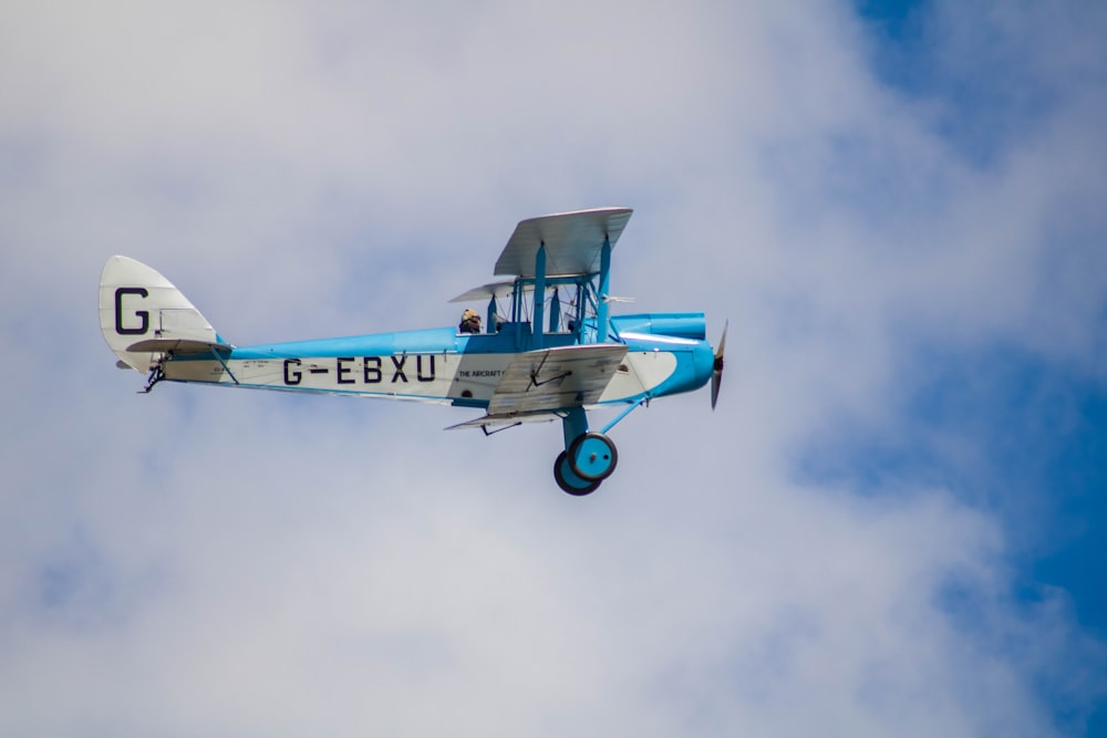 a small blue and white airplane flying in the sky