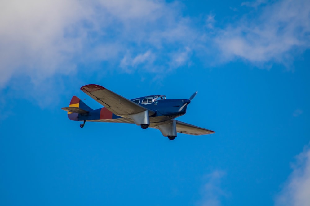 a small airplane flying through a blue sky