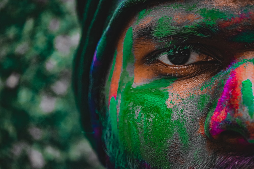 a close up of a man's face with colorful paint all over his face