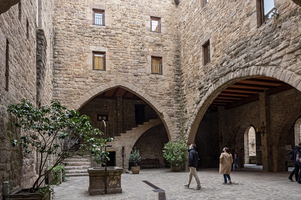 a group of people walking around a stone building