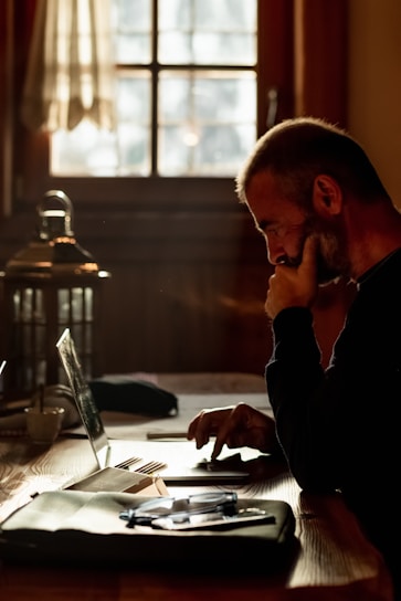 A contemplative writer at a desk surrounded by books and a laptop, with a soft natural light.