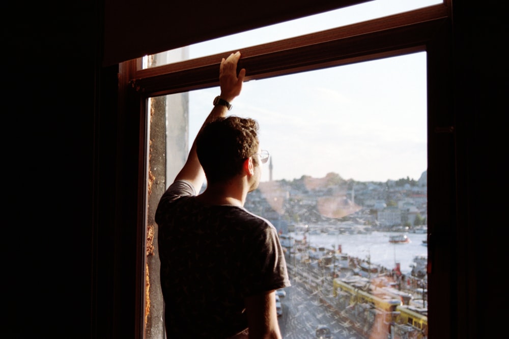 a man looking out a window at a city