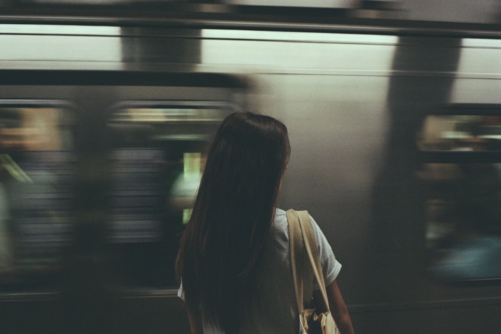 a woman with a backpack is waiting for a train