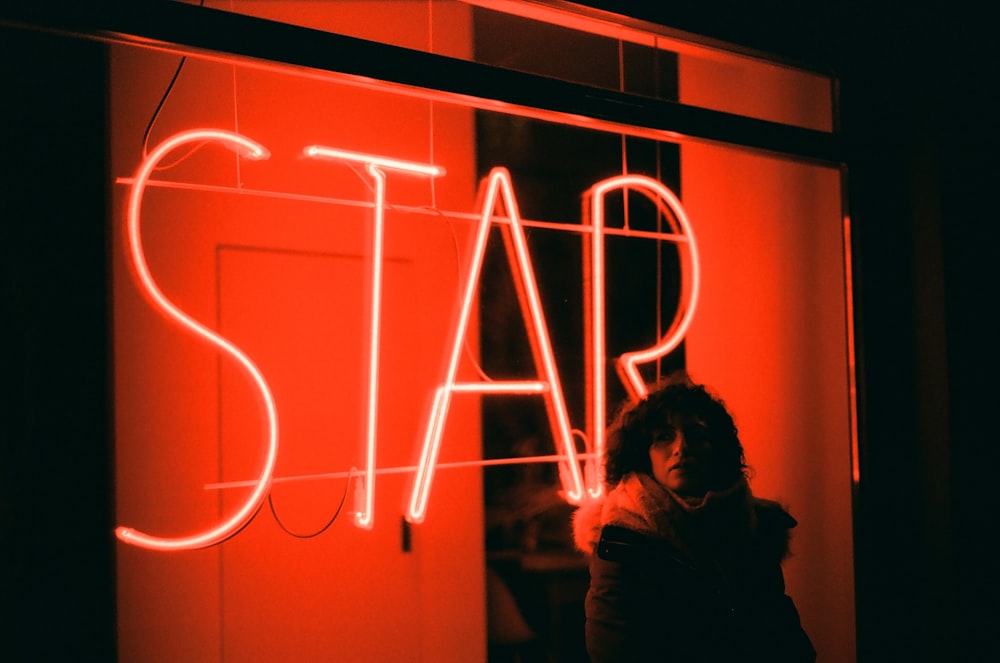 a woman standing in front of a neon sign