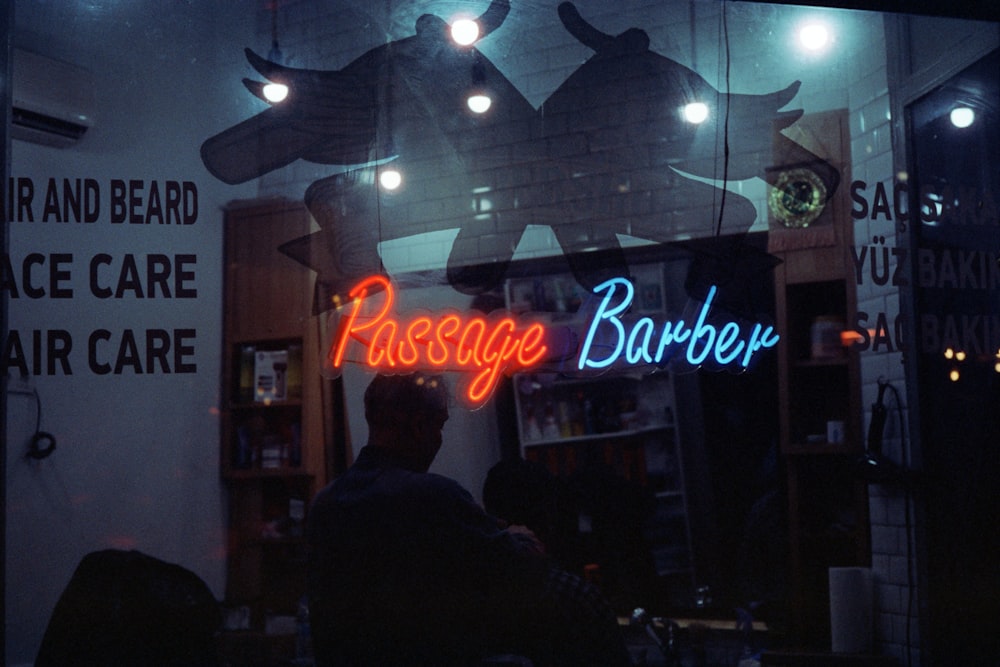 a barber shop with a neon sign in the window