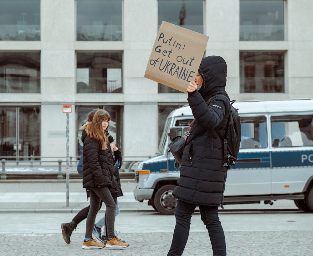 a protester holding a sign in front of a police car