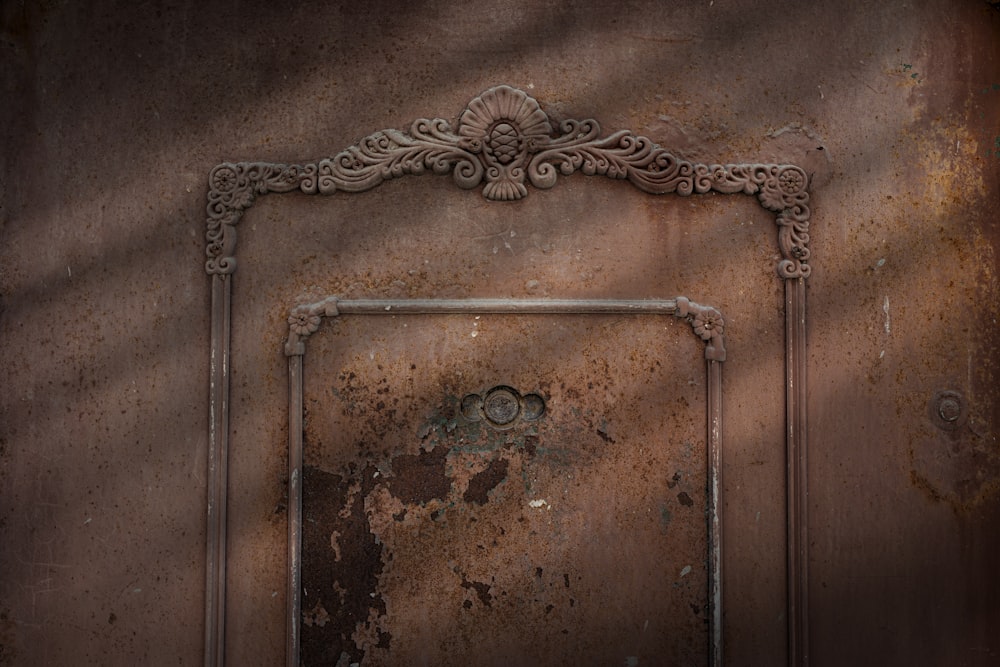 a rusted metal door with a decorative frame