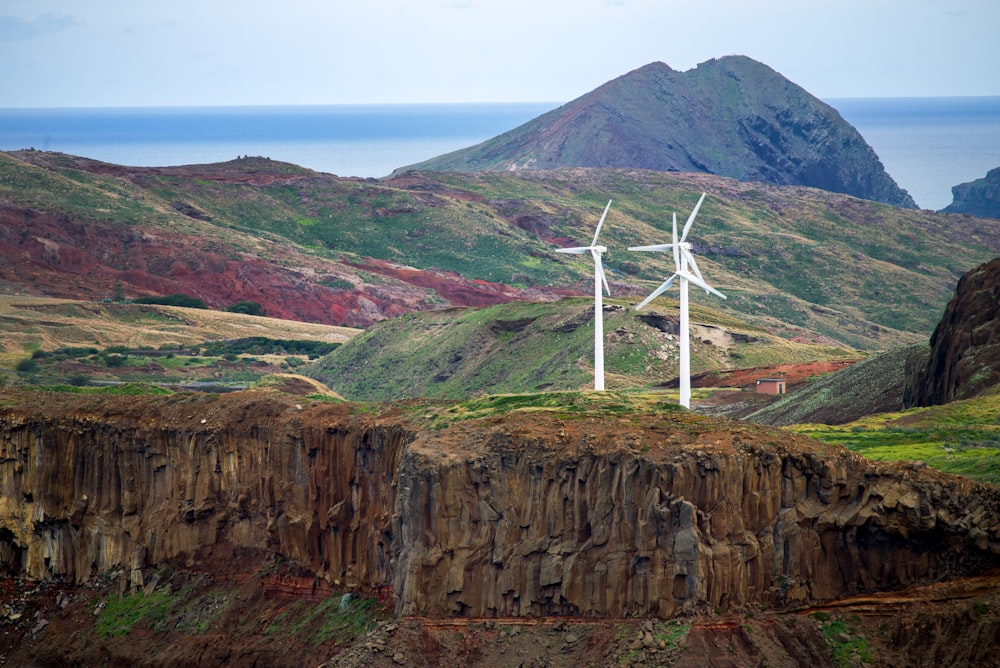 a group of windmills on a hillside near the ocean